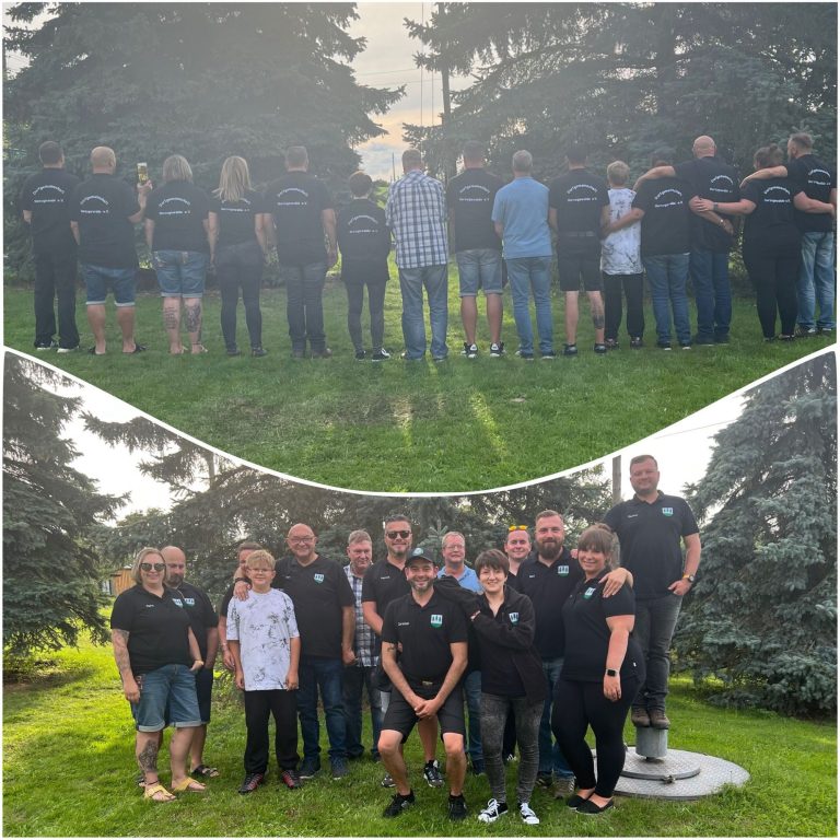Gruppenfoto von Personen, die in einem Garten im Freien stehen, einige mit Rückansicht.