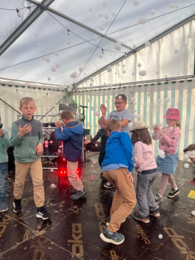 Kinder tanzen und spielen in einem Zelt, umgeben von Seifenblasen.