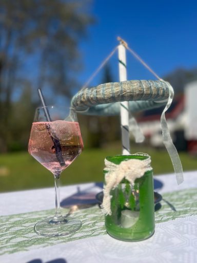 Ein rosa Getränk in einem Glas neben einer grünen Kerze im Freien.