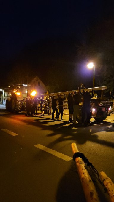 Nachtaufnahme von einer Gruppe von Menschen neben Feuerwehrfahrzeugen und Lichtern.