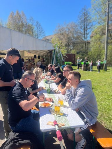 Menschen bei einem Picknick im Freien, sitzend an Tischen und genießend Essen und Getränke.