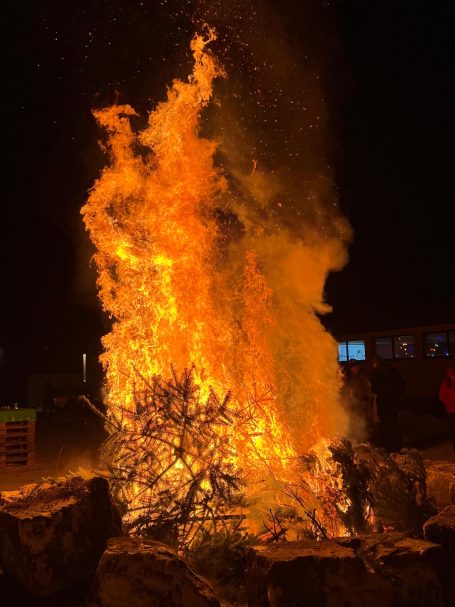 Großes Feuer mit lodernden Flammen und Funken in der Nacht.