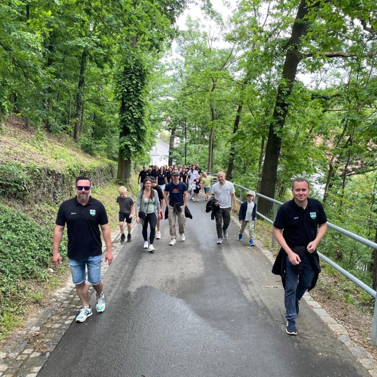 Gruppe von Menschen geht einen schattigen Waldweg entlang.