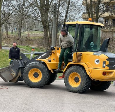 Mann steigt aus einem gelben Radlader, während ein weiterer Mann zuschaut.