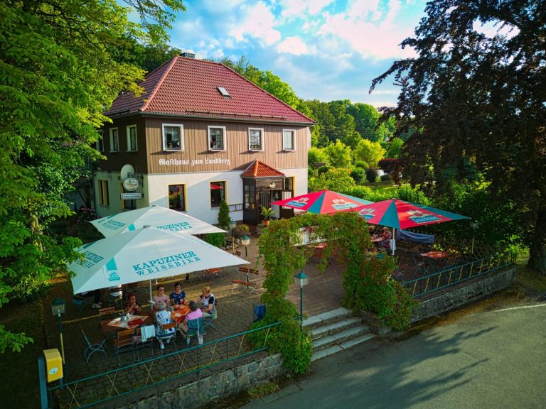 Gemütliches Restaurant mit Terrasse, umgeben von Bäumen und Sonnenschirmen.